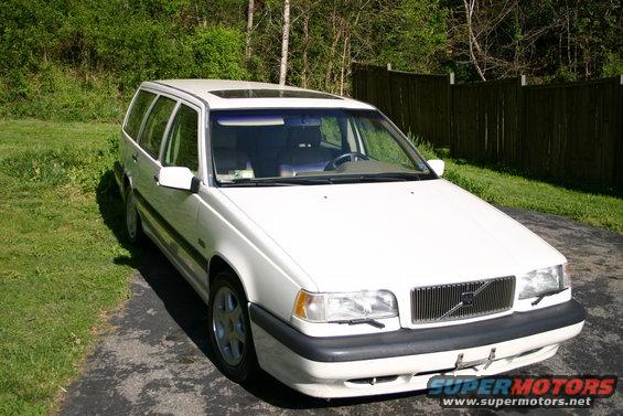 White 1997 Volvo 850 wagon parked on driveway with trees and fence in background