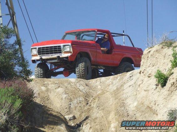 Red 1978 Ford Bronco with roll cage driving off-road