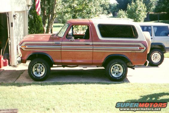 Red and white 1979 Ford Bronco parked next to a white SUV