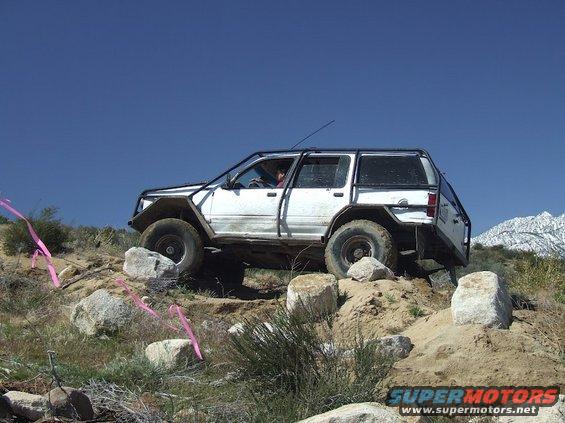 White off-road SUV with roll cage navigating rocky terrain