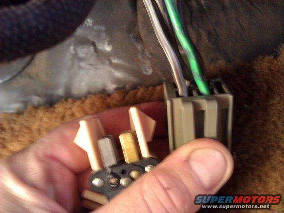 Hand holding a male electrical connector with wires, about to plug into a female connector