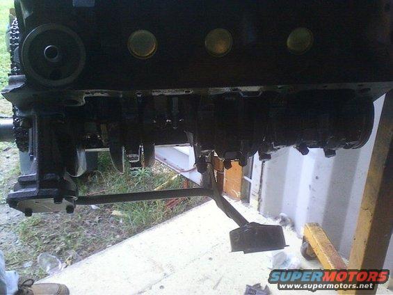 Black engine block with exposed crankshaft and oil filter housing, supported by a yellow engine stand