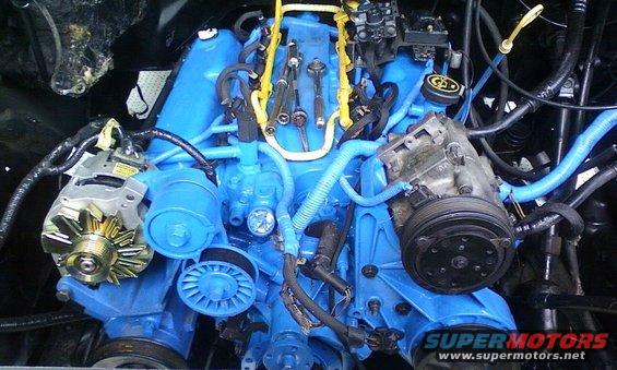 Engine bay with bright blue painted engine components, alternator, and AC compressor