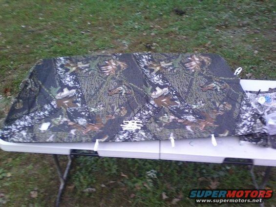 Mossy Oak camouflage fabric laid out on a white folding table outdoors