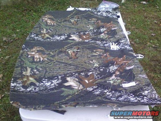 camouflage fabric draped over a white surface, with a plastic bag of items on top