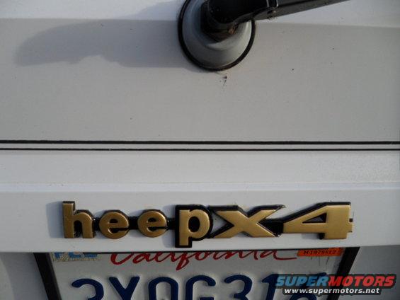Gold 'Jeep 4x4' badge on white tailgate above California license plate
