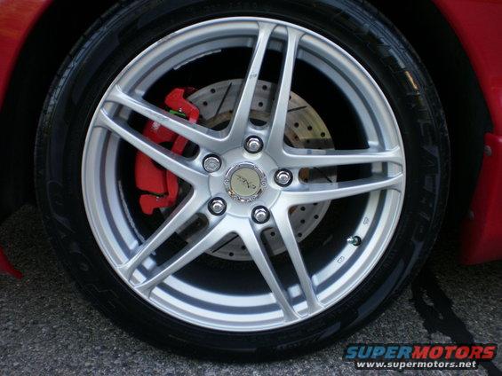 Close-up of a silver five-spoke wheel with a red brake caliper visible behind it
