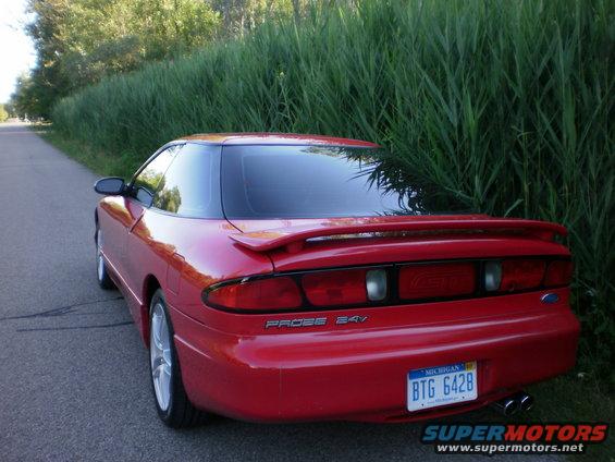 Red 1996 Ford Probe GT parked on a road next to tall grass