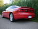 1996 Ford Probe - Rear-left view of a red 1996 Ford Probe coupe parked on an asphalt road with greenery in the background.