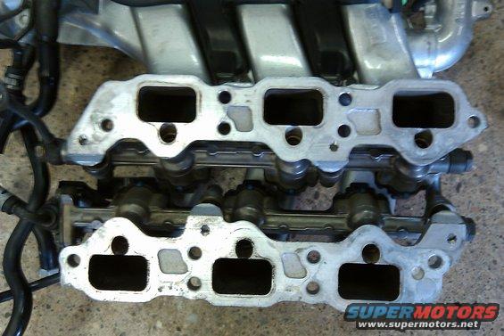 Engine intake manifold with fuel injectors visible, metal and black hoses