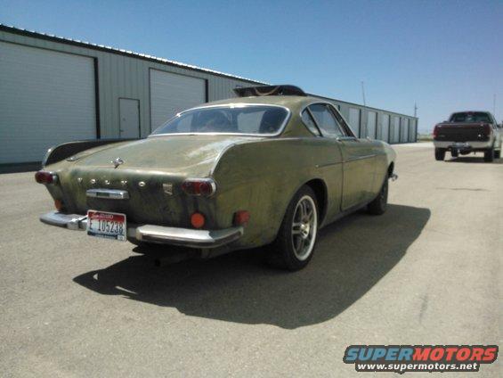 Olive green 1969 Volvo P1800 coupe, rear 3/4 view, showing faded paint and a license plate