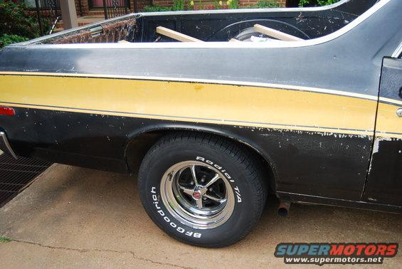 Side view of black and yellow 1975 Ford Ranchero rear wheel and bed
