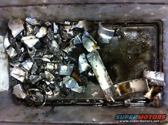 Pile of shattered metal engine bearings in a greasy bin