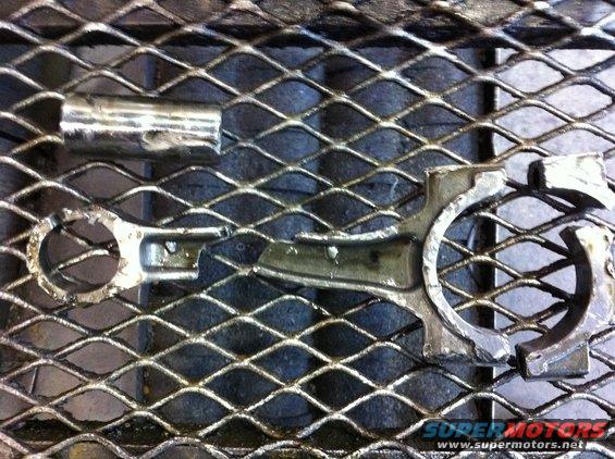 Broken engine connecting rod and cap on a metal grate