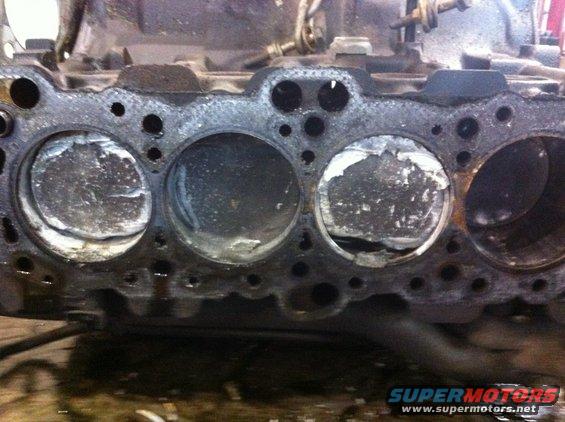 Engine block with four damaged pistons visible