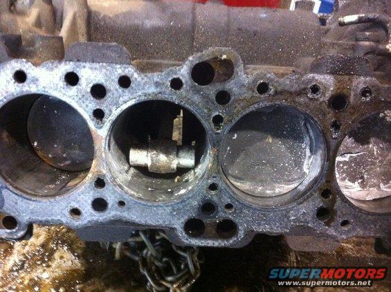 Engine block with pistons visible in cylinders, showing wear and damage