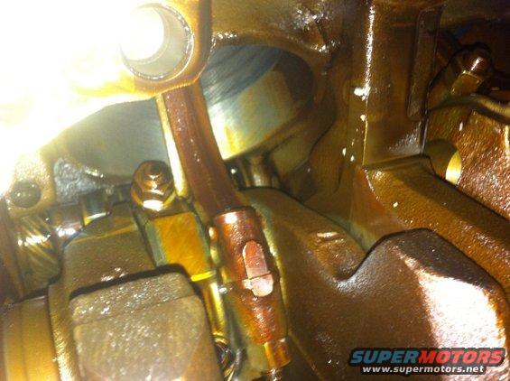 Close-up of engine oil pan and connecting rod with oil