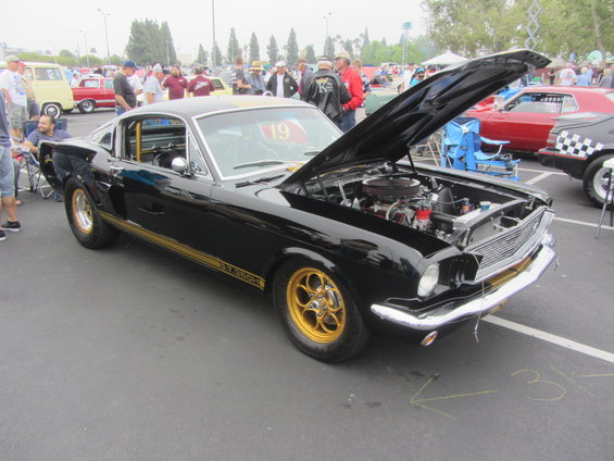 Black 1966 Ford Mustang Shelby GT350 with gold stripes and wheels, hood open