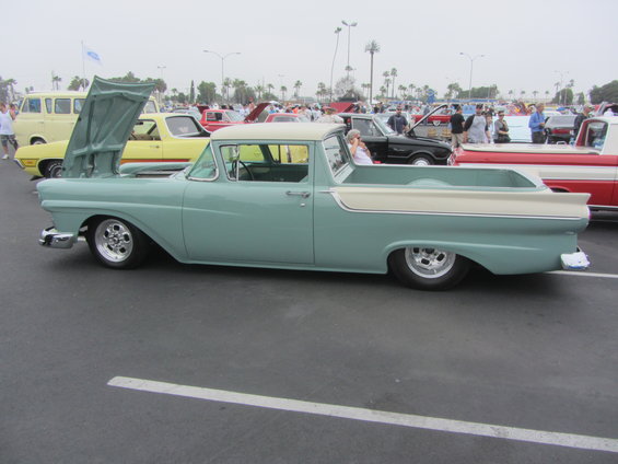 Light blue and cream 1957 Ford Ranchero with hood up, parked at a car show