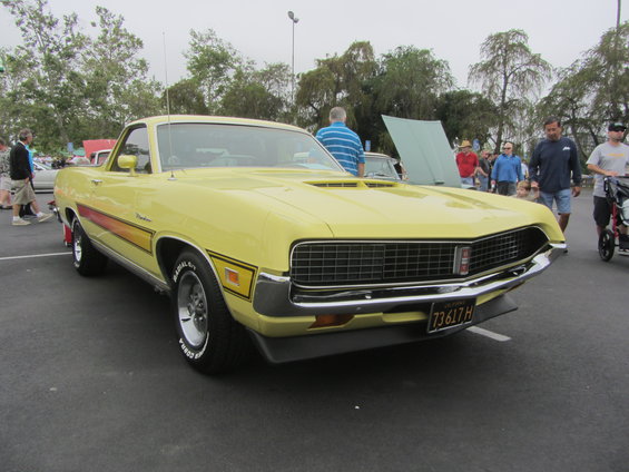 Yellow 1970 Ford Ranchero with side stripe and hood scoop, parked outdoors