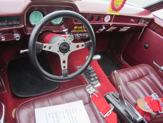 1964 Ford Ranchero interior with red seats, aftermarket steering wheel, and floor shifter