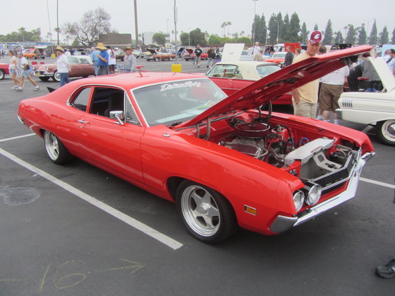 Red 1970 Ford Torino GT with hood open, parked at car show