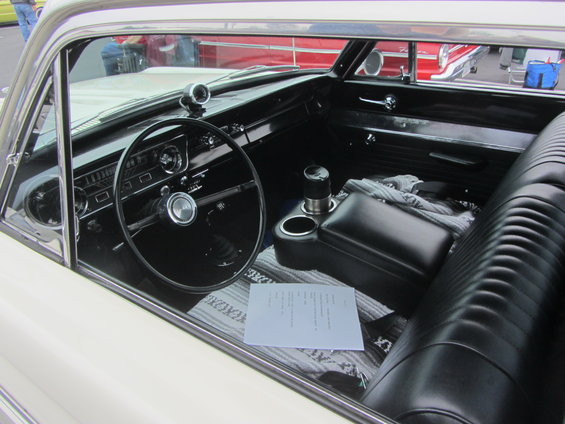 1964 Ford Ranchero interior with black seats, dashboard, steering wheel, and a document on the passenger seat