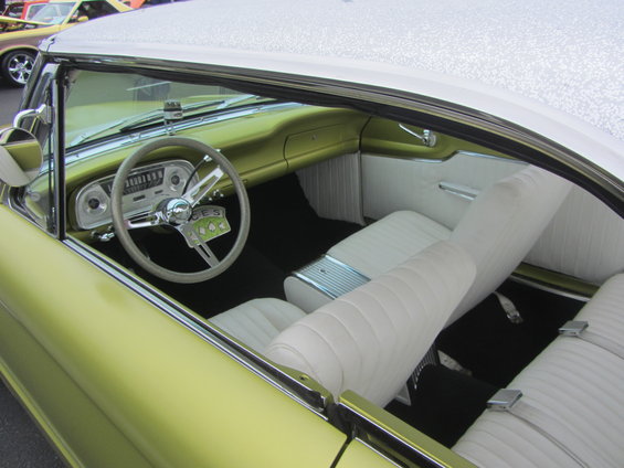 Interior of a light green car with white seats and a white roof. Another car is visible in the background