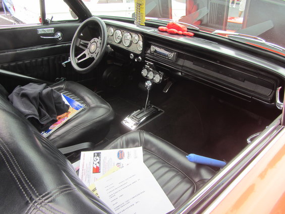 Interior of a classic car with black vinyl seats, a steering wheel, and a dashboard with gauges
