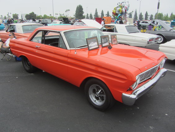 Orange 1964 Ford Ranchero with a white roof and hood scoop, viewed from the front three-quarter angle