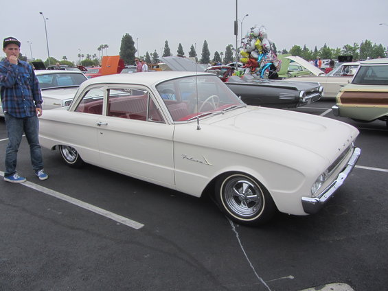 White 1960 Ford Falcon sedan with red interior parked at a car show