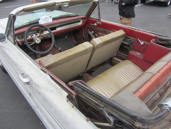 Interior of a classic convertible with tan seats and red trim. Steering wheel and dashboard visible