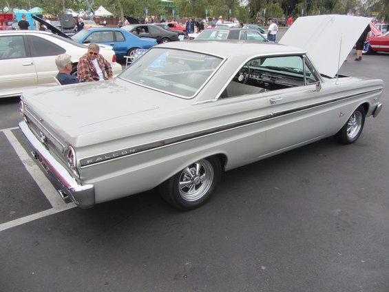 Silver 1964 Ford Falcon coupe, hood open, parked in lot with other cars