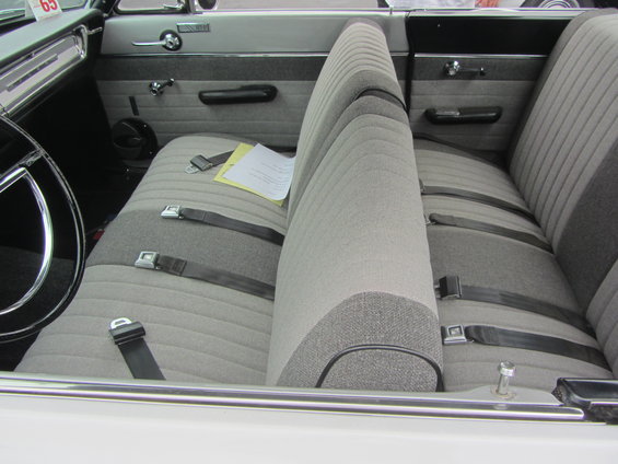 Car interior with bench seat, seatbelts, and a paper on the seat