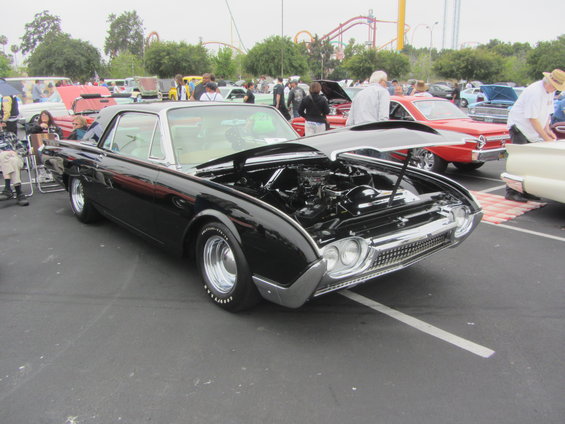 Black 1961 Ford Thunderbird with hood open, parked at a car show