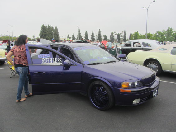 Purple sedan with custom rims and doors open, a woman stands beside it