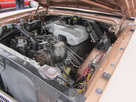 Engine bay with V8 engine, hoses, and wiring visible. Hood is open