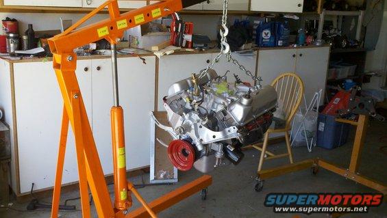 Engine suspended by hoist, red pulley visible