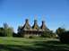 2002 Ford Taurus - A historic building with three distinctive chimneys stands under a clear blue sky, surrounded by green grass and trees.