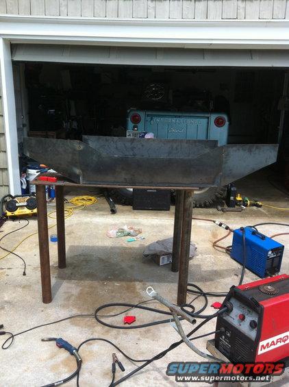 Metal bumper project on table in garage with welding equipment. Blue International Scout in background