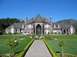 2002 Ford Taurus - A grand stone mansion is set against a clear blue sky, with lush green lawns and formal gardens.