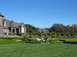 2002 Ford Taurus - A person strolls through a formal garden with a fountain and a large brick estate under a clear blue sky.