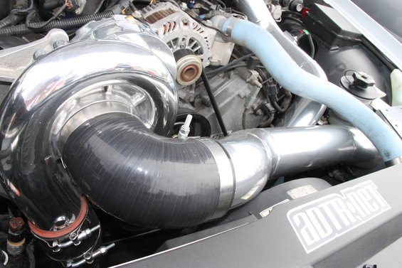 engine bay with large chrome turbocharger and blue intercooler piping