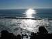 2002 Ford Taurus - Waves break on the rocky shore with the sun glinting off the ocean surface.