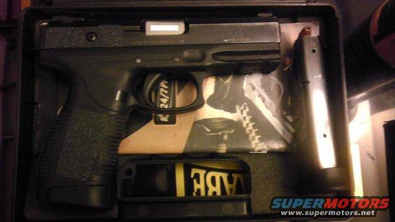 Pistol and magazine in a black case with foam padding. Text on the pistol reads '24/7 Pro'
