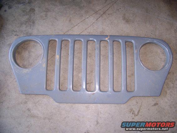 Gray Jeep grille with seven vertical slots and two circular headlight cutouts. Supermotors.net logo at bottom right