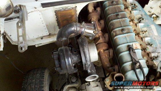 close-up of turbocharger and exhaust manifold on an engine, with part of a tire visible