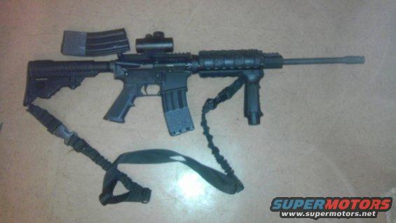 AR-15 style rifle with two magazines, red dot sight, vertical foregrip, and sling