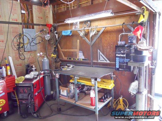 Garage workshop with welding equipment, workbench, and tools hanging on the wall
