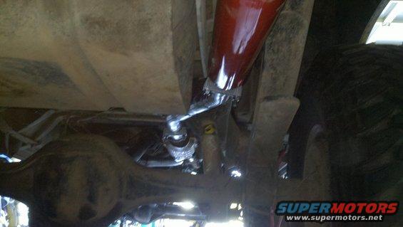 Underside view of vehicle suspension showing a red shock absorber and differential